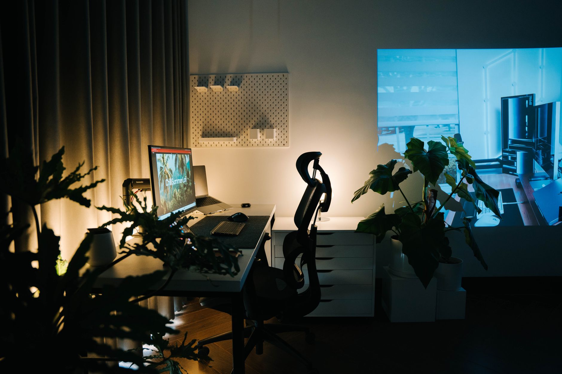 Bureau à domicile chaleureux avec ordinateur, plantes et éclairage d'ambiance, propice à un travail de prospection organisé.